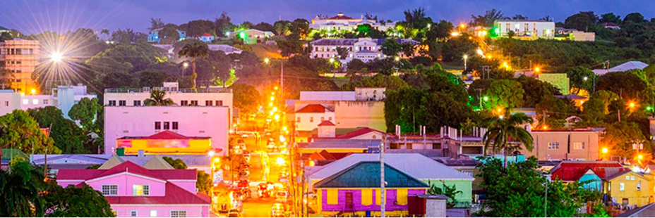 Wide view of Capital City, St. John's, colorfully vibrant architecture in Antigua and Barbuda illuminated at night.